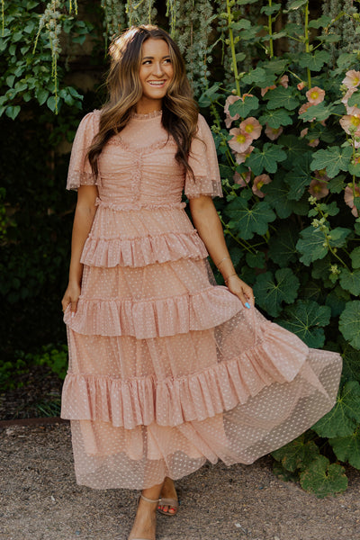 An alternate shot of this blush pink modest dress with a swiss dot fabric, flutter sleeves, and an illusion neckline.