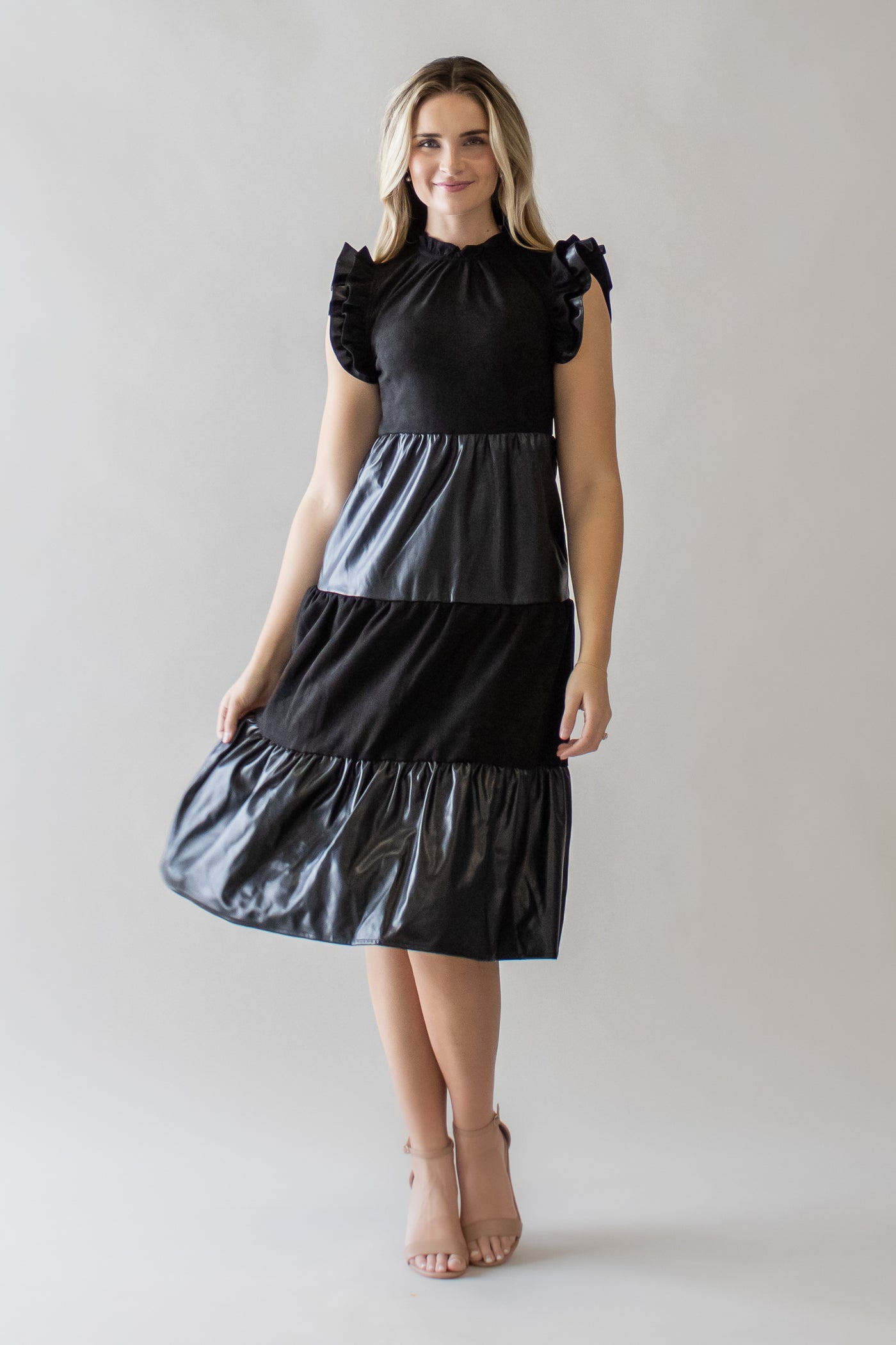 This is a black modest dress with a tiered skirt and different layers of pleather and fabric.