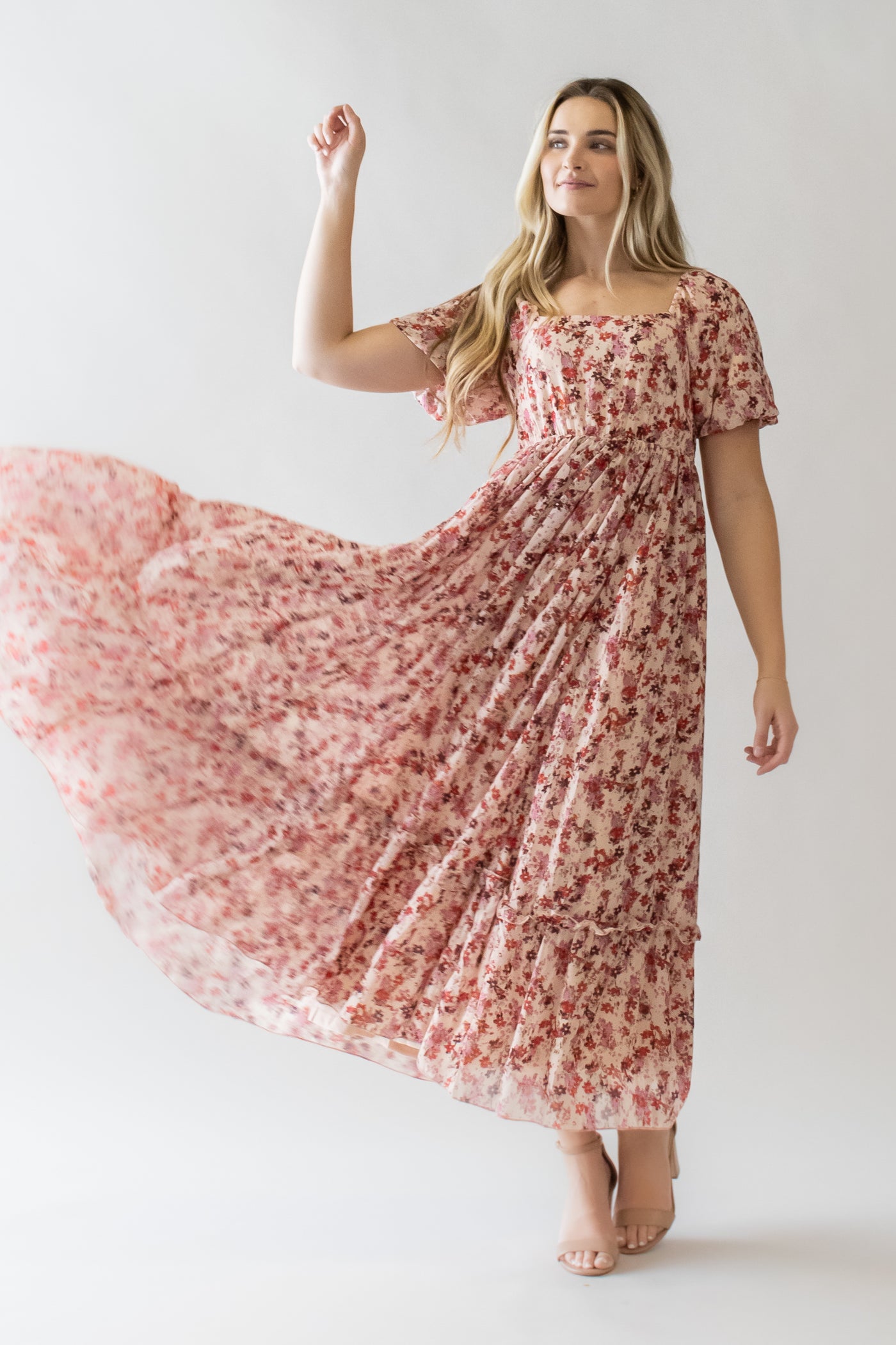 This is a blonde model flinging around her pink floral dress with a square neckline and tiered skirt.