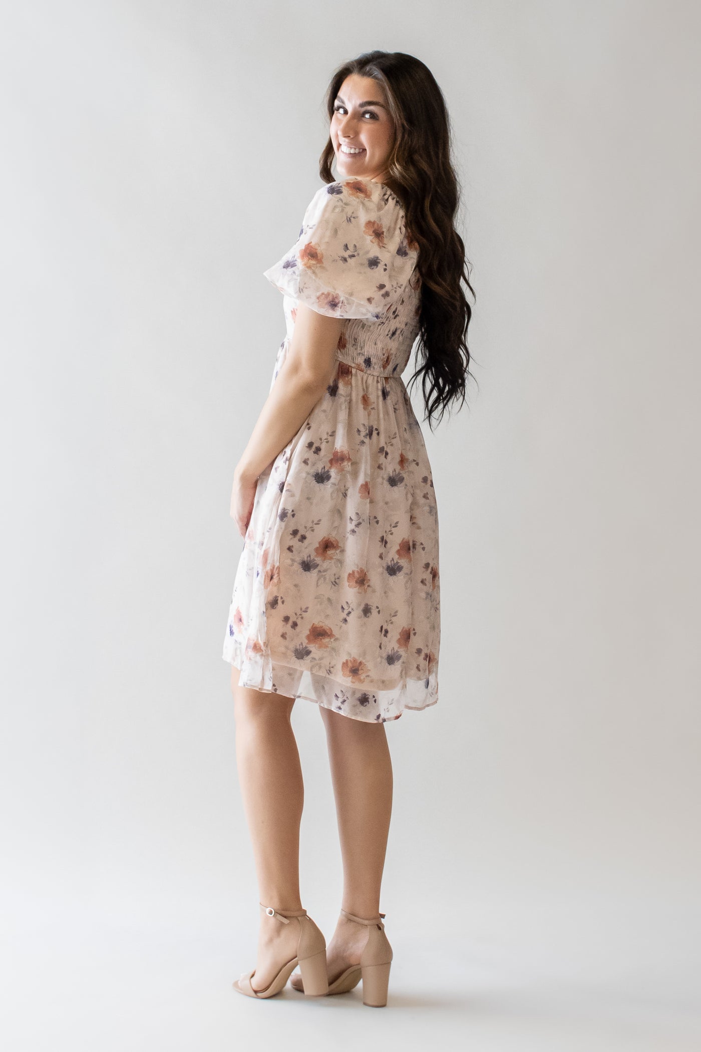 This is a modest dress with pink floral details and a knee length skirt.