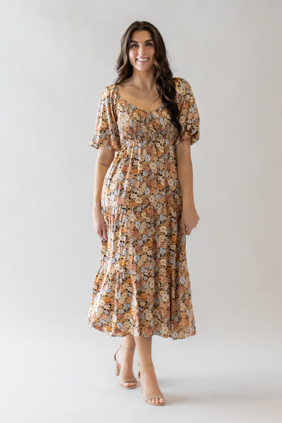 This is a modest dress with orange and yellow floral details and a smocked bodice.