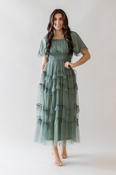 This is a modest dress in a dusty green color and ruffle details and a ruched bodice.