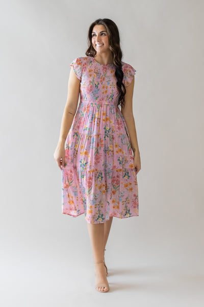 This is a modest dress with pink floral details and a smocked bodice.