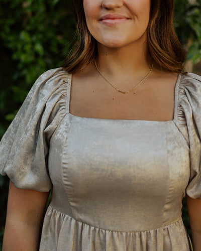 An up close angle of the modest dress in a gold color of the square neckline and puff sleeves.