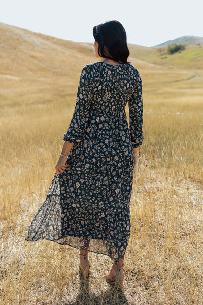 A back shot of a floral green modest dress with long sleeves and a maxi length skirt.