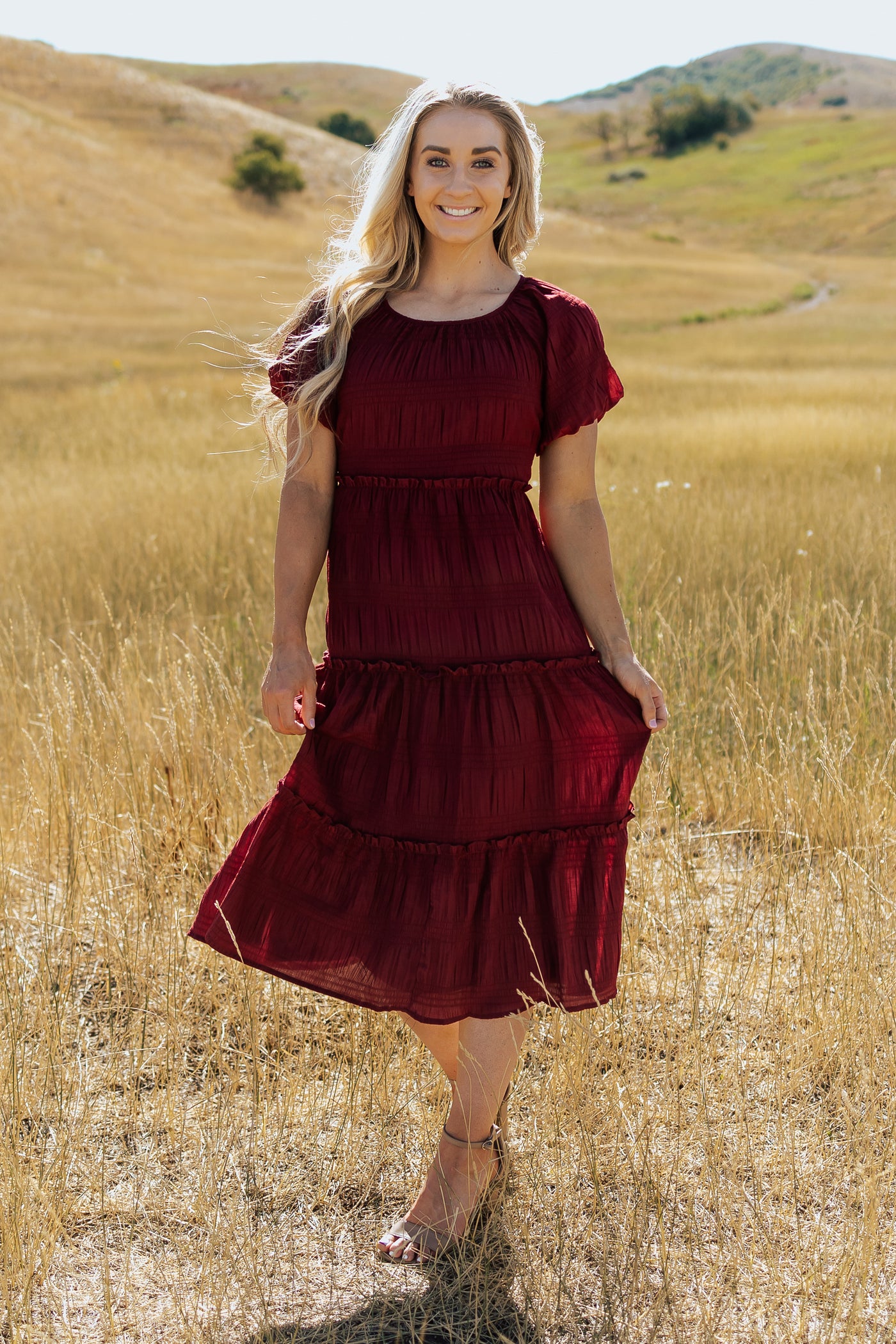 A front shot of red, modest dress with a textured fabric and tiered skirt.