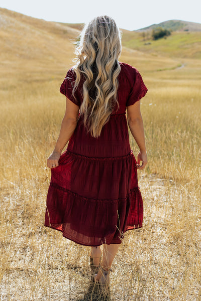 A back shot of a red, modest dress with a puff sleeve and texture fabric.