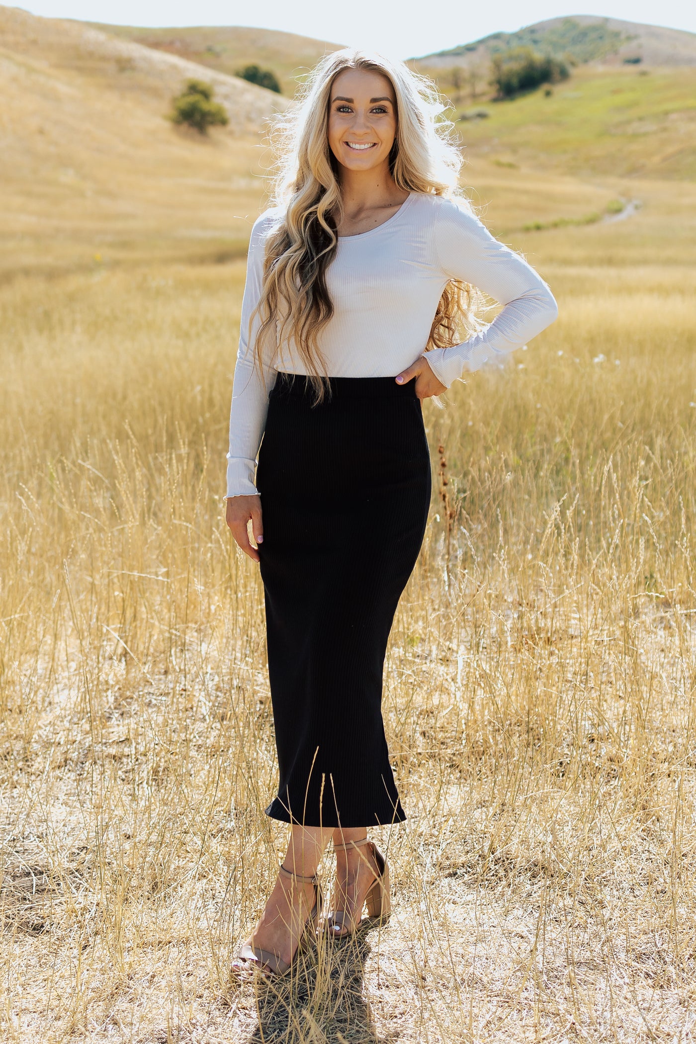 A front shot of a cream, ribbed shirt paired with a black maxi pencil skirt. 