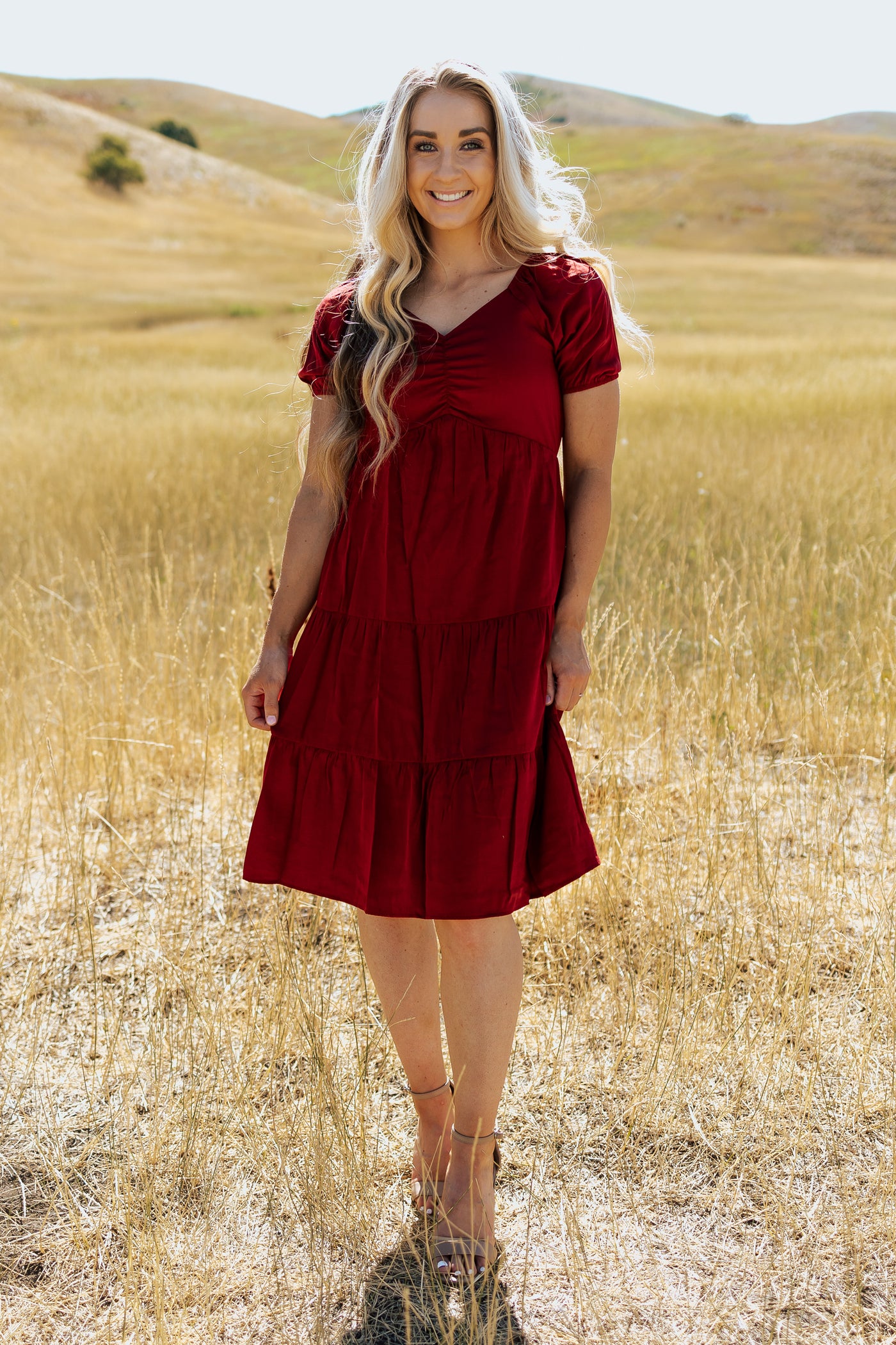 A front shot of a red, modest dress with a ruched bodice and a knee-length skirt.