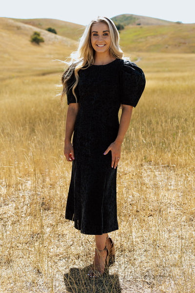A front shot of a black denim modest dress with a leopard print and puff shoulder sleeves.