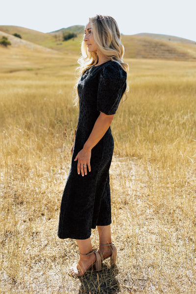 A side shot of a black denim modest dress with a leopard print and puff shoulder sleeves.