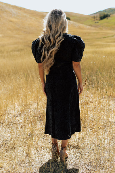 A back shot of a black denim modest dress with a leopard print and puff shoulder sleeves.