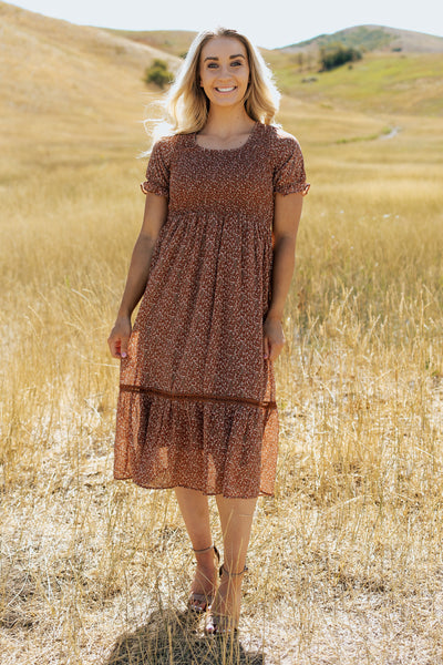 A front shot of a modest dress with a scoop neckline, smocked bodice and a fun floral  pattern.
