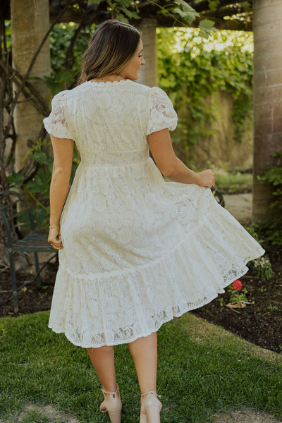 A back shot of our gorgeous, lacy modest dress featuring shear, puff sleeves, and a defined waistline.
