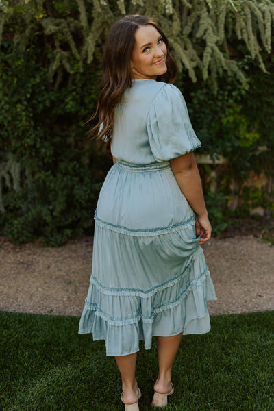 An alternate back shot of this midi blue modest dress with puff sleeves and fun layered tiers.