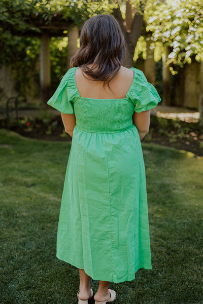 A back shot of a green, modest dress with a smocked, square backside and a defined wasitline.