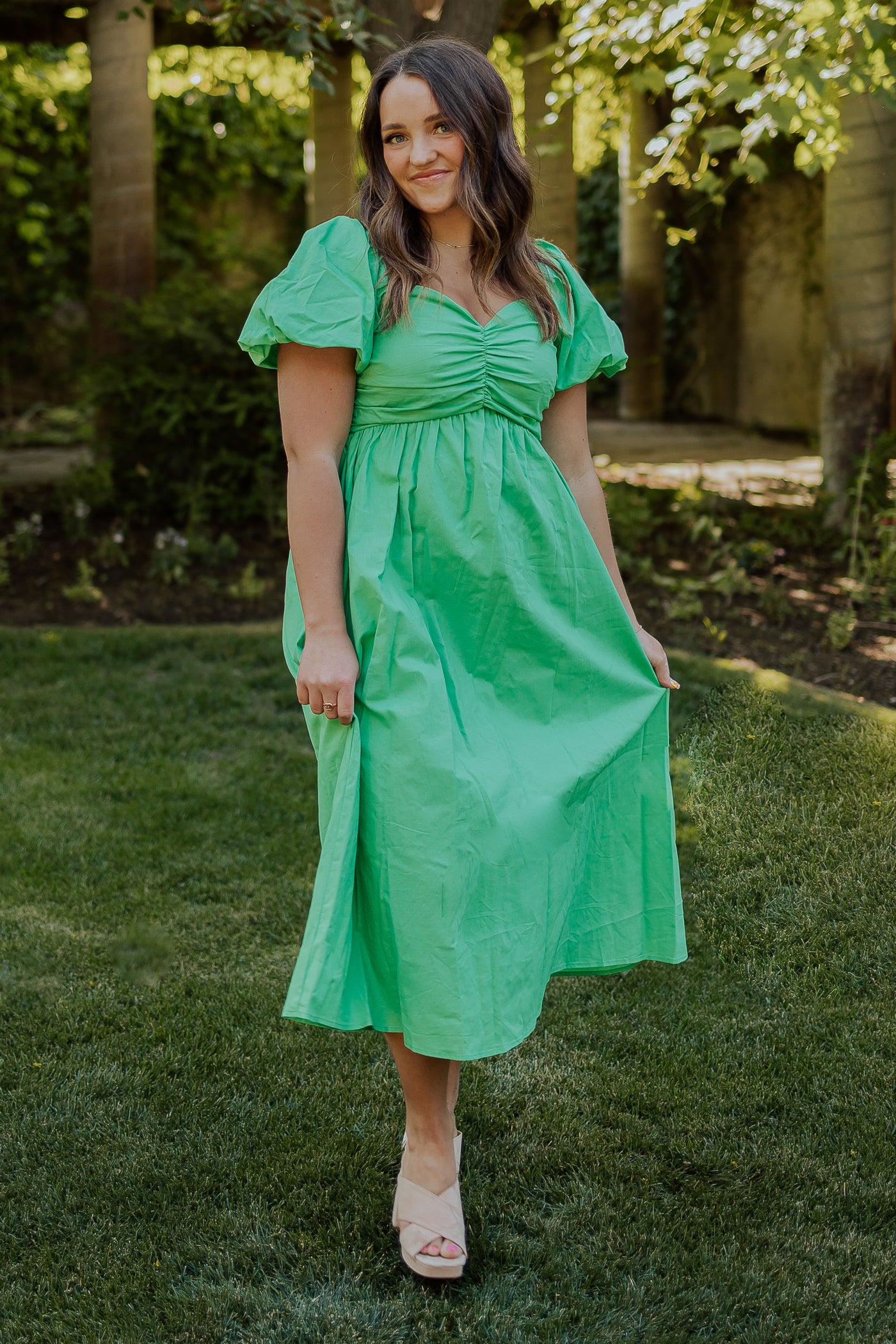 A front shot of a green, modest dress with a sweetheart neckline, defined waistline, and puff sleeves.