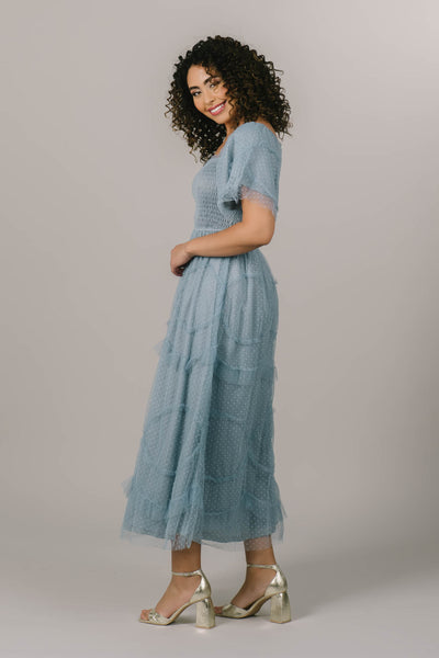 This modest dress features a smocked bodice and soft tulle and polka dot details.