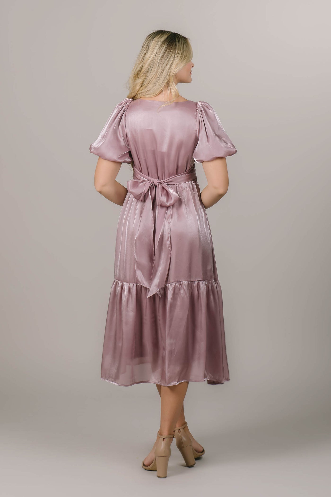 This is a back shot of a modest bridesmaid dress with a bow in the back and a tiered midi skirt.