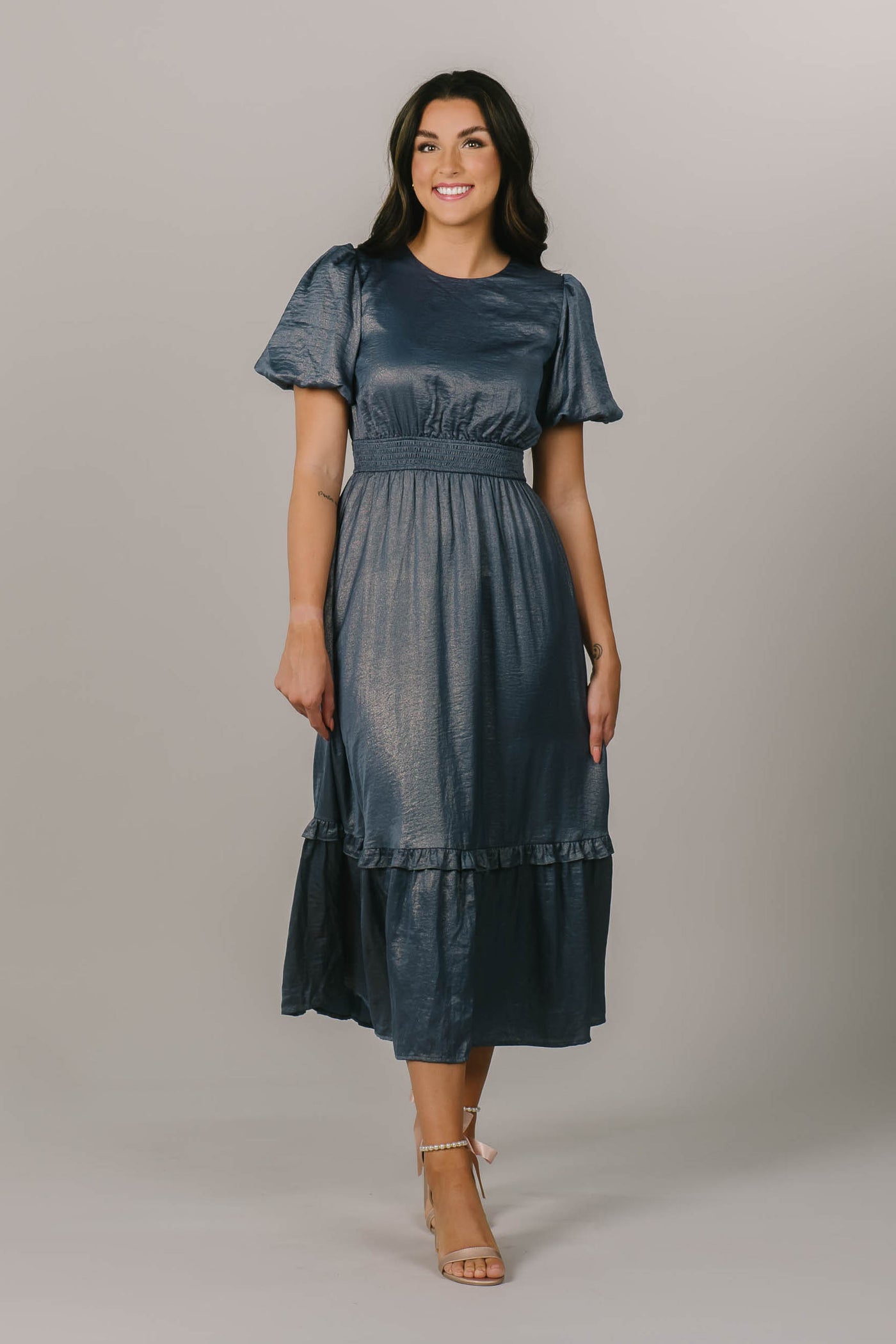 This is a modest bridesmaid dress with a blue shimmery fabric and defined waistline.