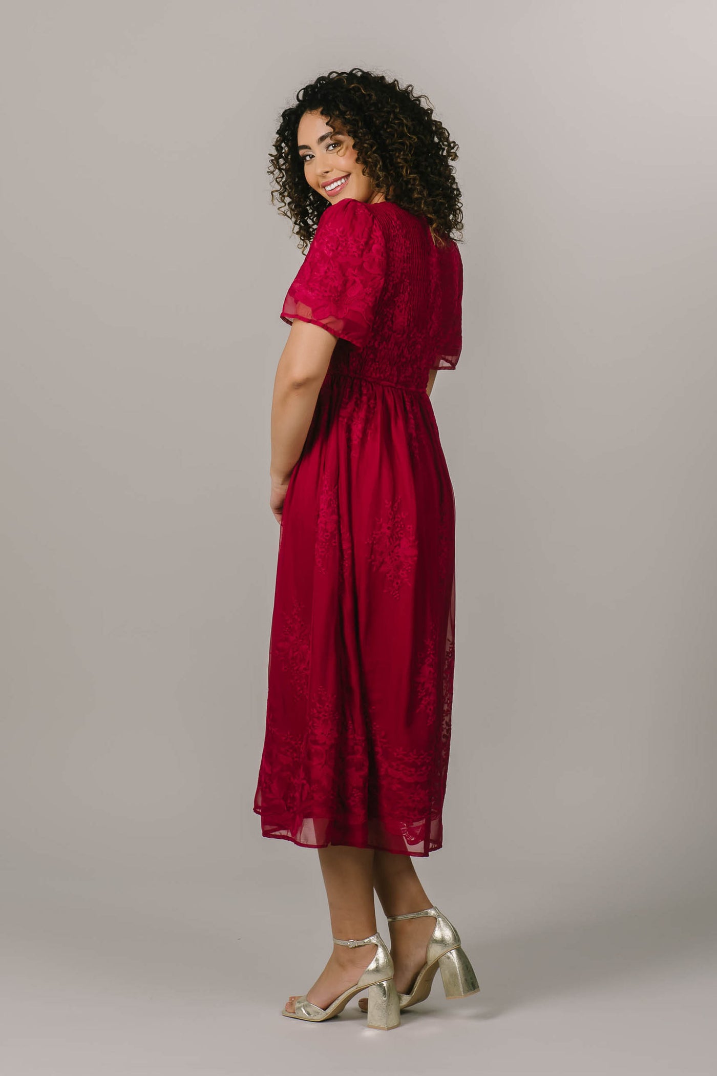 This modest dress is a bright magenta color, has embroidered flowers, and is a midi length.