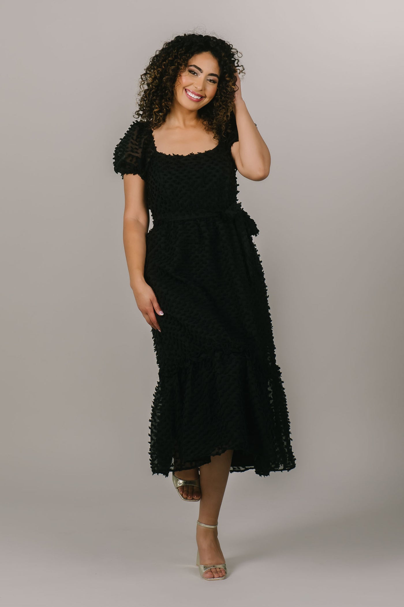 This is a modest black dress with polka dot details and a fun bow around the waist.
