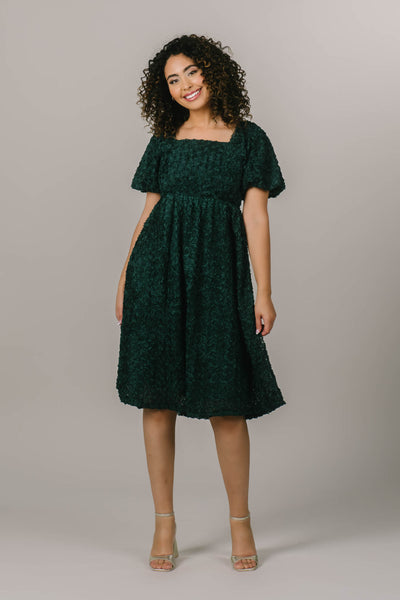 This modest dress features a rose textured fabric and a square neckline.
