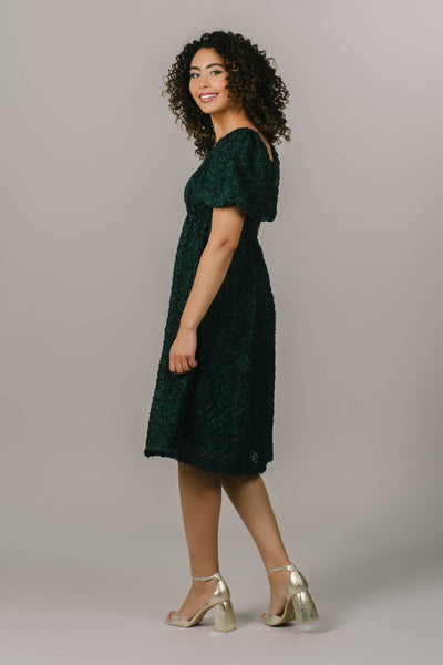 This modest dress has rose textured fabric and a square neckline, and a puff sleeve.