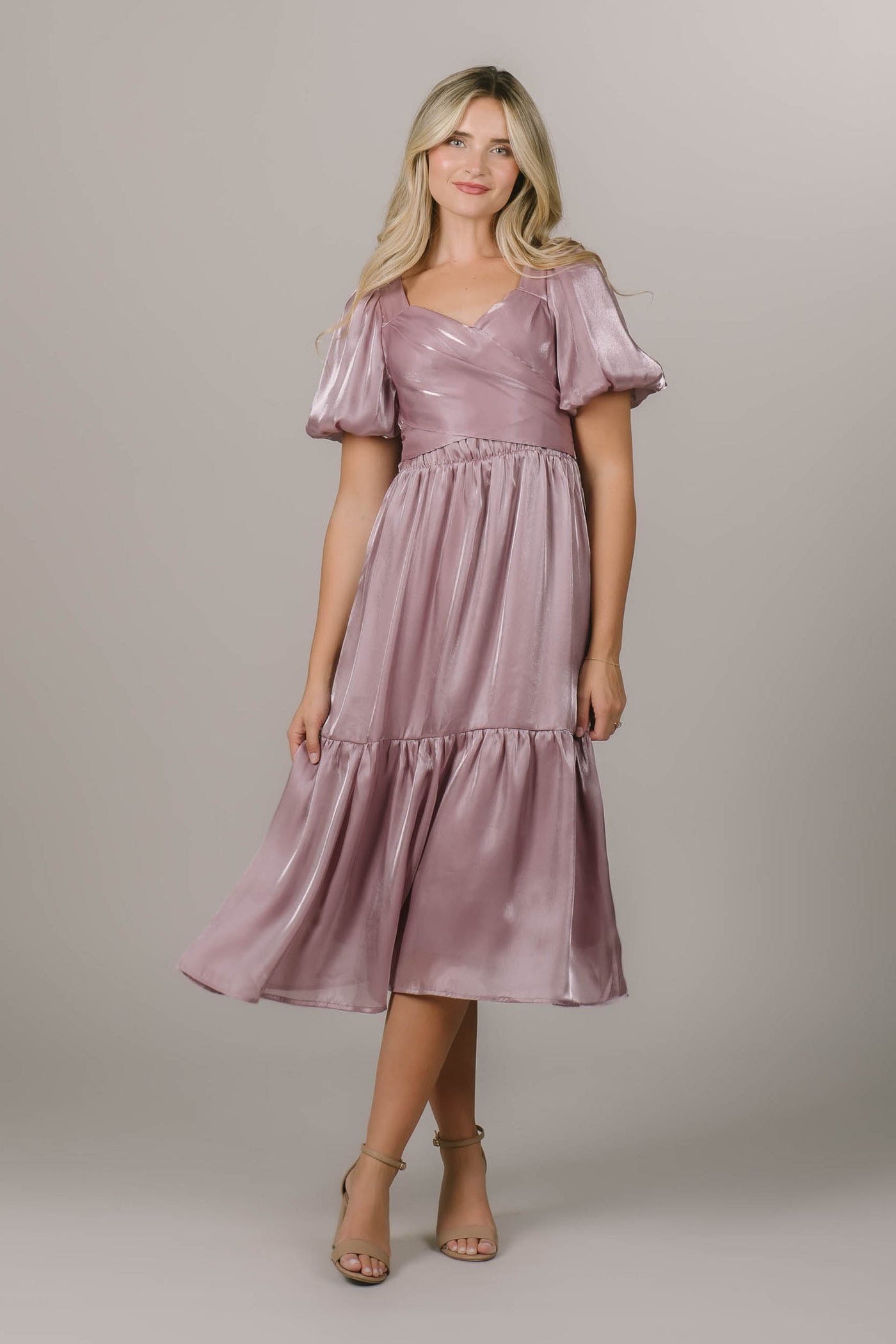 This is a modest bridesmaid dress with a wrap bodice and a shimmery pink fabric.