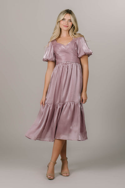 This is a modest bridesmaid dress with a wrap bodice and a shimmery pink fabric.