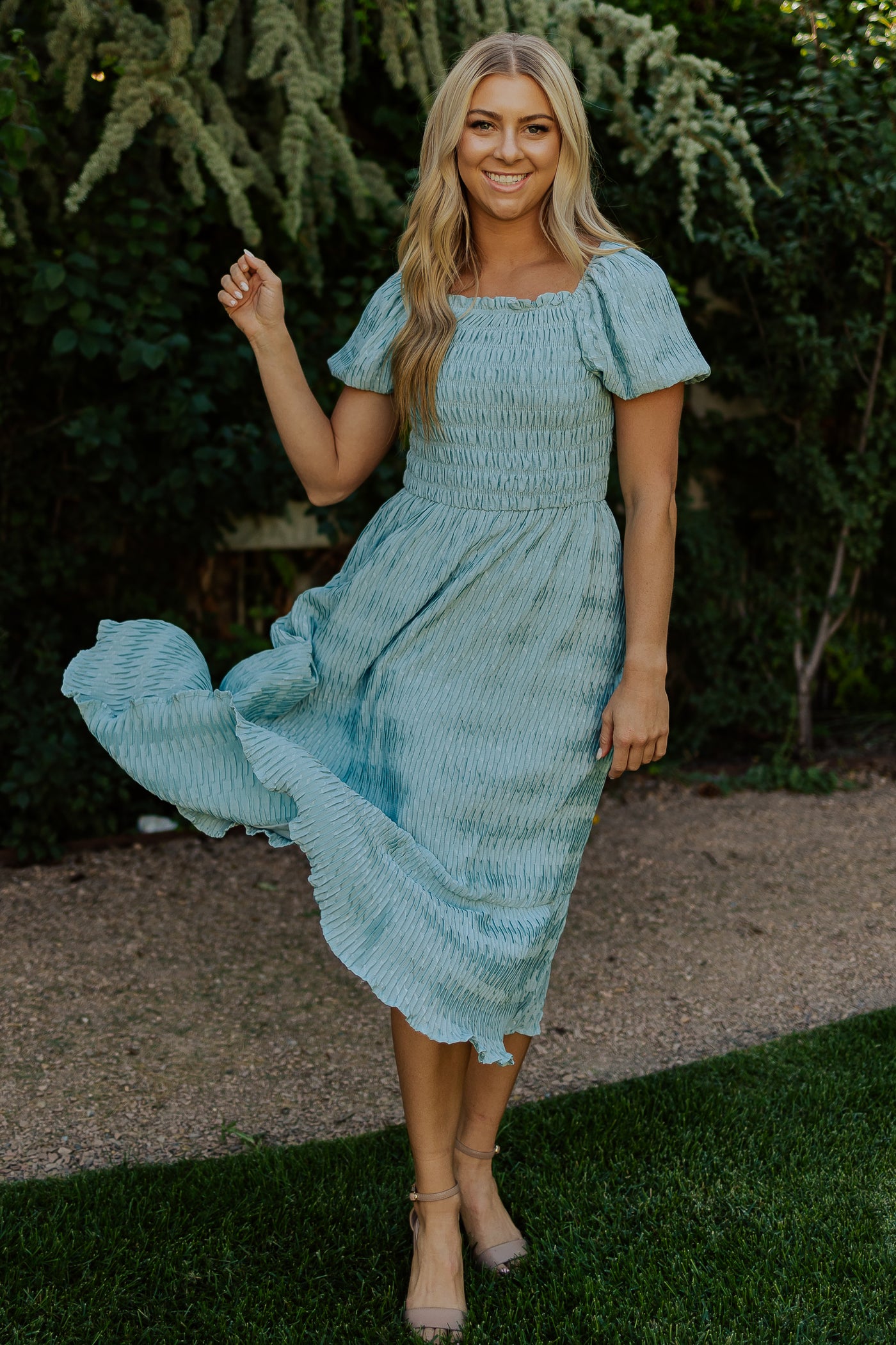 A front shot of a blue, modest dress with a textured fabric, a square neckline, and puff sleeves.