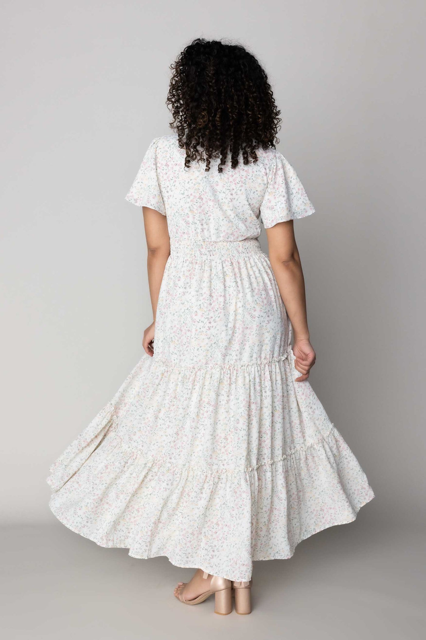 This modest dress features a defined waistband and floral details.
