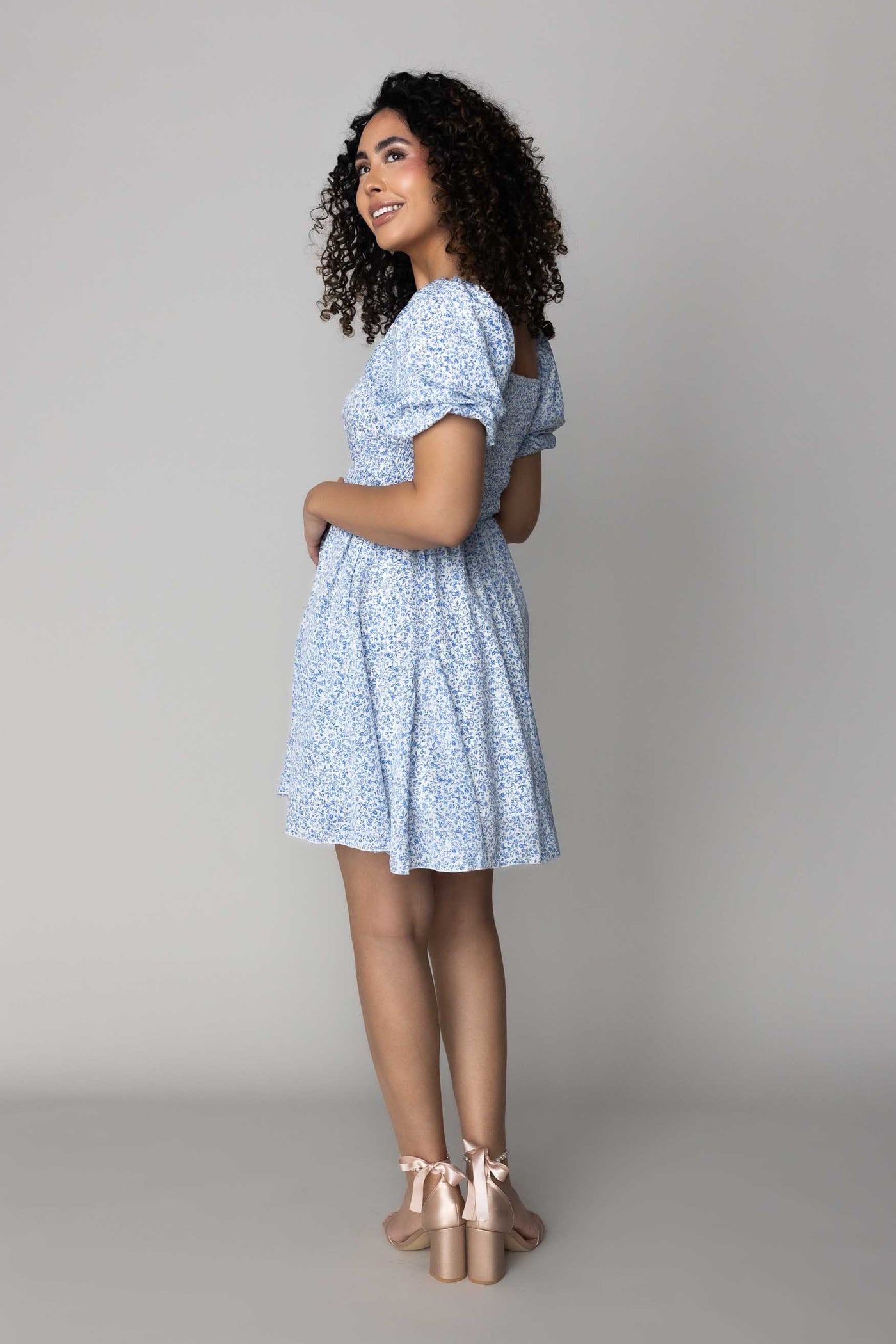 This is a backshot of a modest blue dress with floral details and a smocked back.