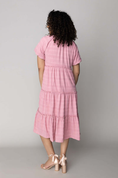 This modest dress features a textued fabric, dusty pink color, and a tiered skirt.
