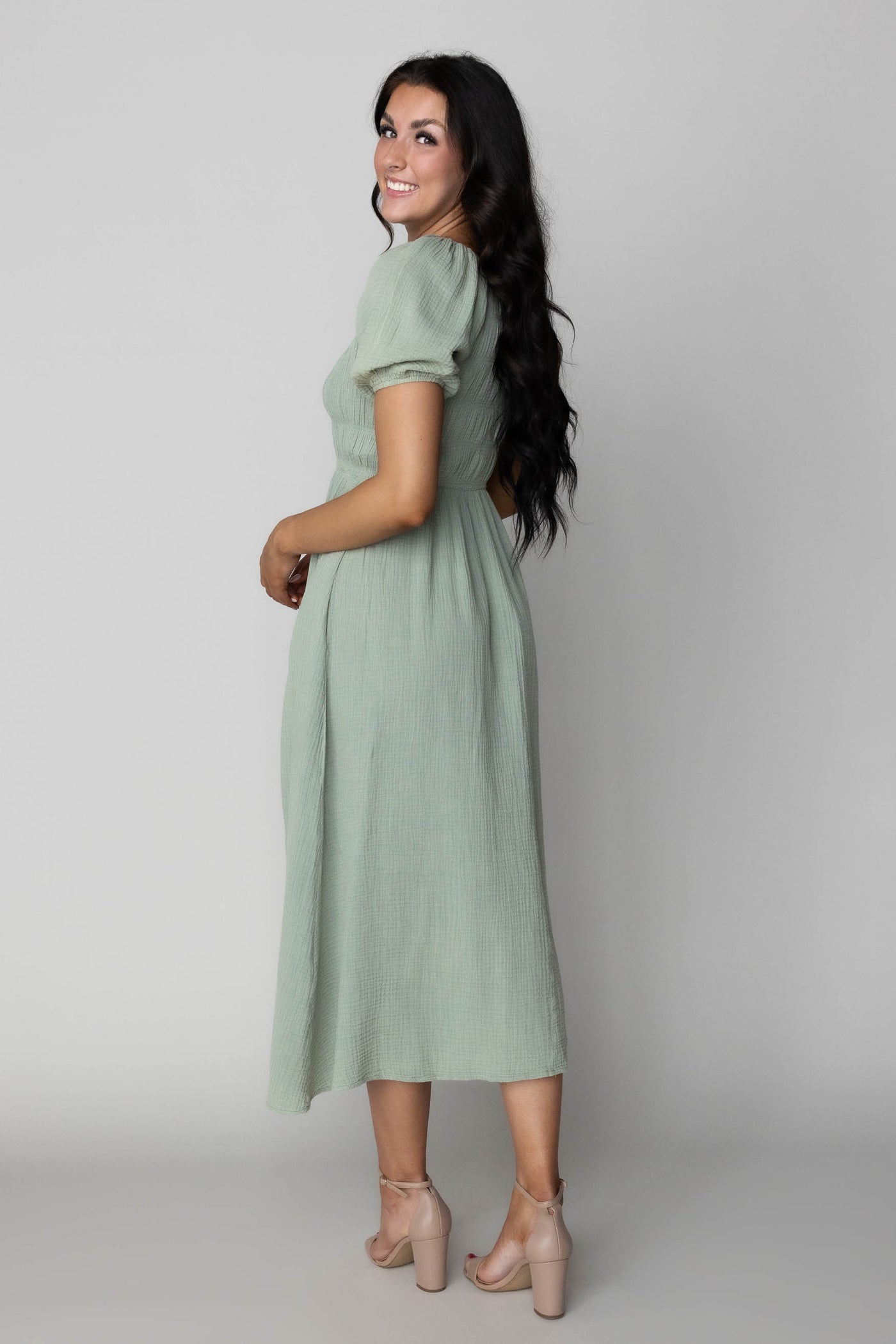 This modest bridesmaid dress has  a smocked bodice and is sage green.