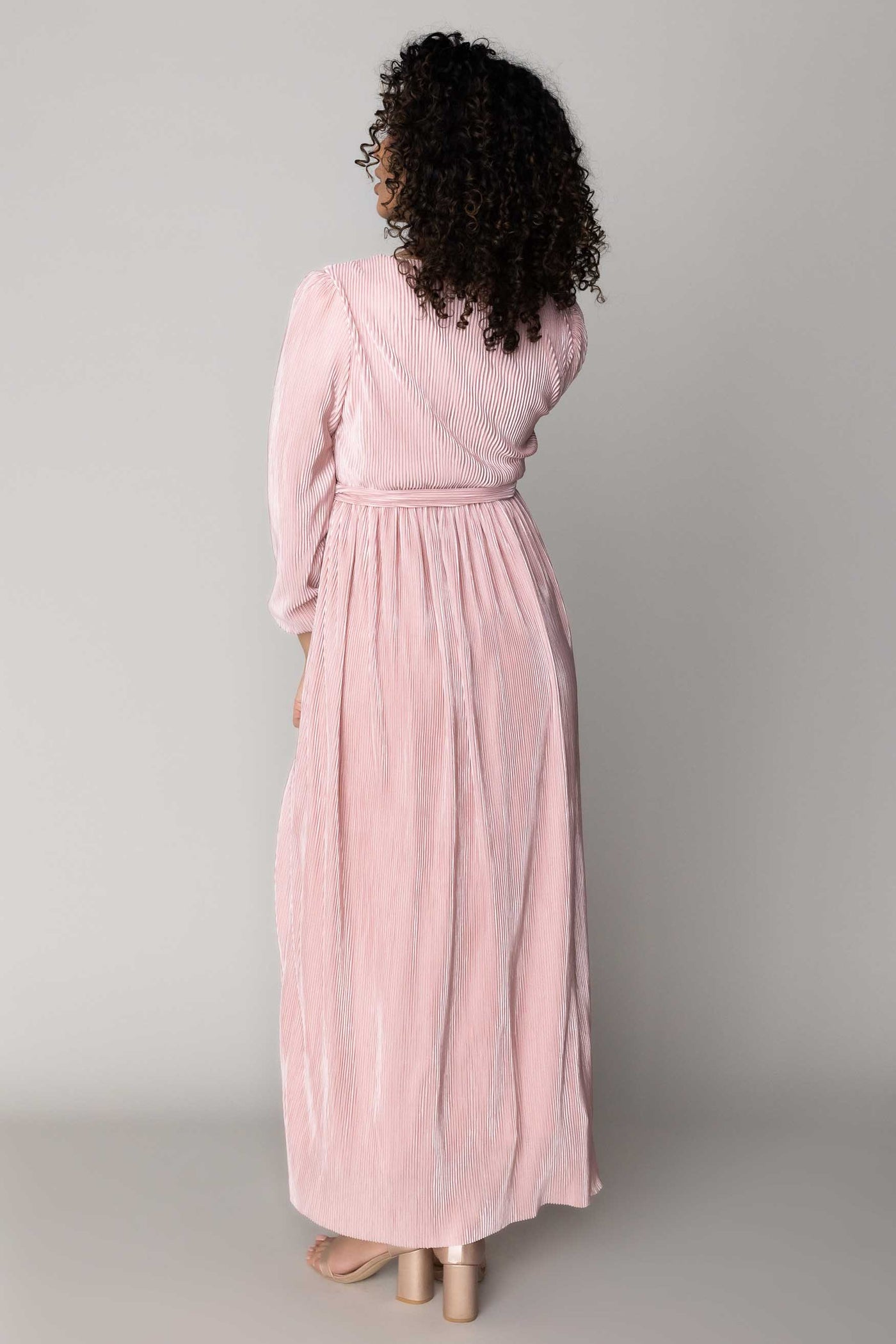 This is a back shot of a modest dress with blush pink details nad a long skirt.