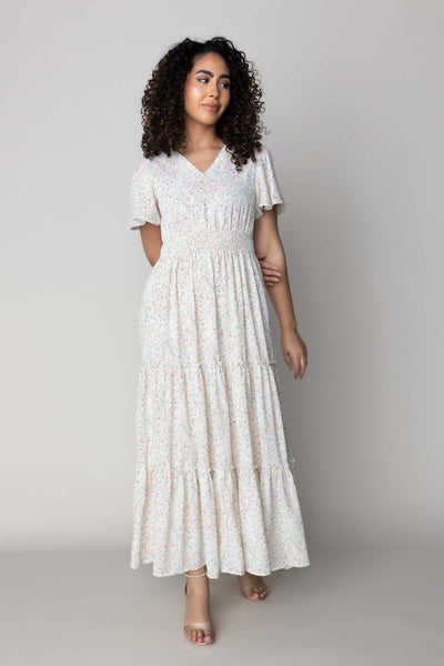 This is a modest white dress with pastel floral details and features a v neckline