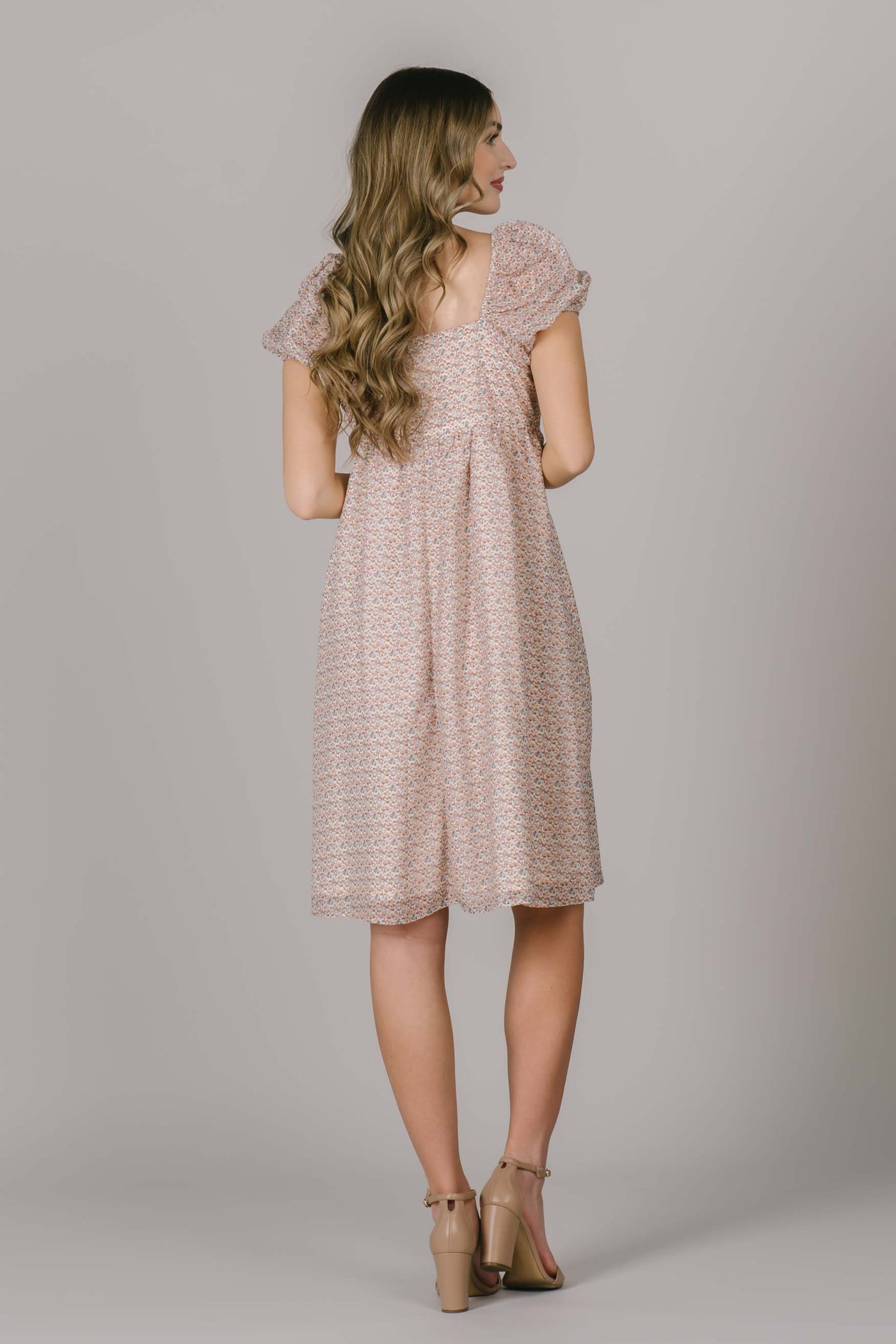 The back of a modest dress with a square backline, puff sleeves, and small floral pattern.