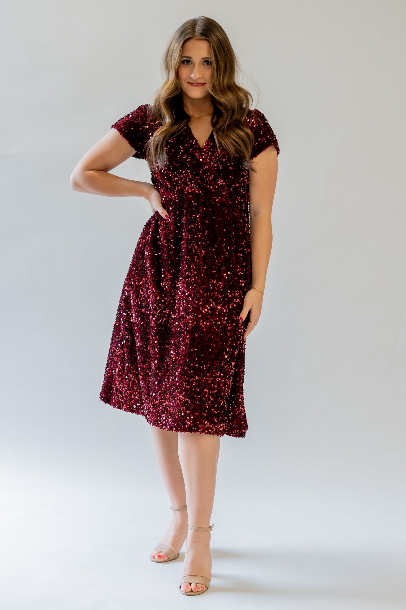 Sparkly modest bridesmaid dress with v-neckline. It is burgundy and has sequins covering the dress. It has a higher waistline.