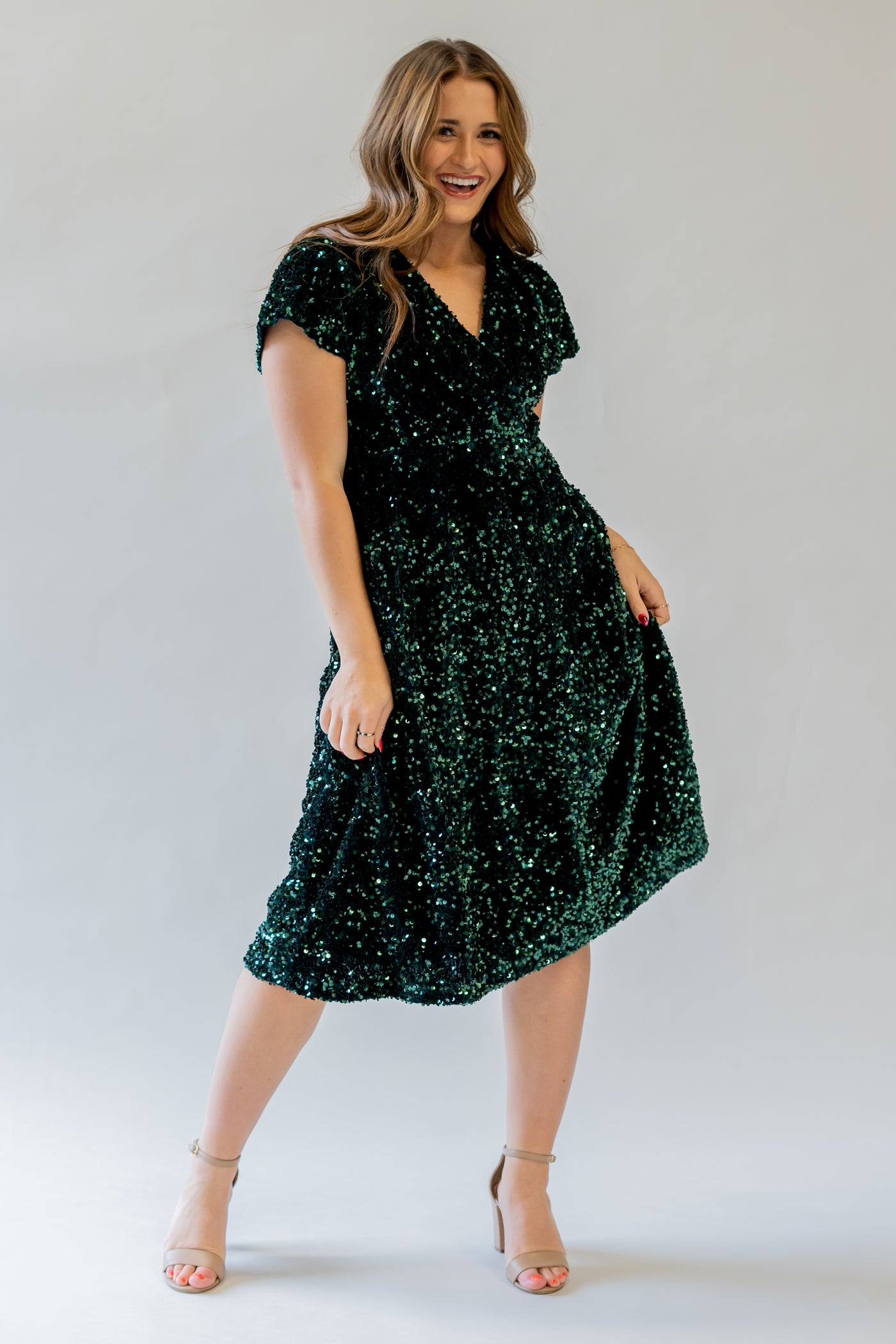 Sparkly modest bridesmaid dress with v-neckline. It is green and has sequins covering the dress. It has a higher waistline.