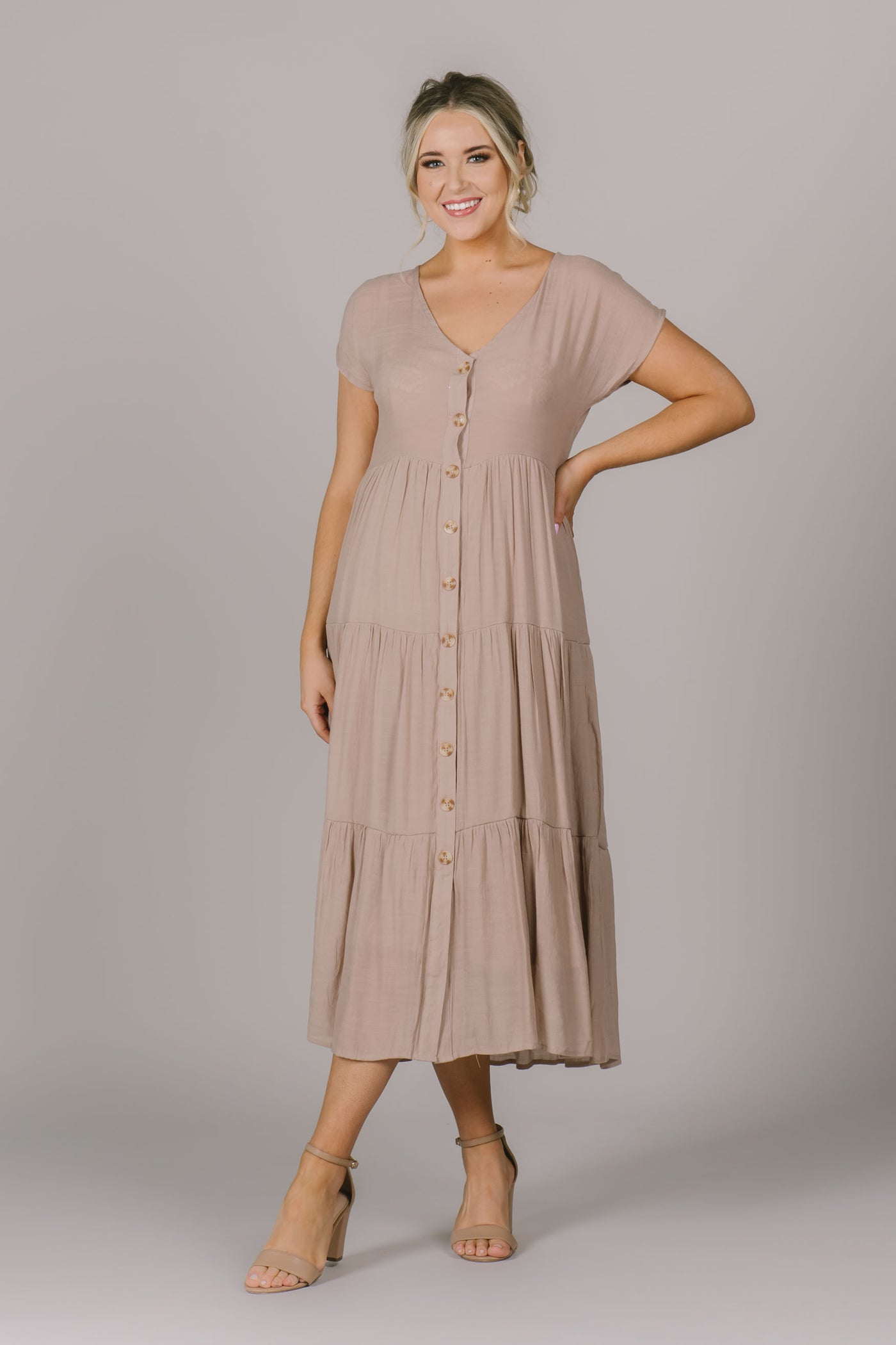 The Emma dress features a V-neck, buttons down the front, and tiered skirt design.