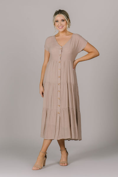 The Emma dress features a V-neck, buttons down the front, and tiered skirt design.
