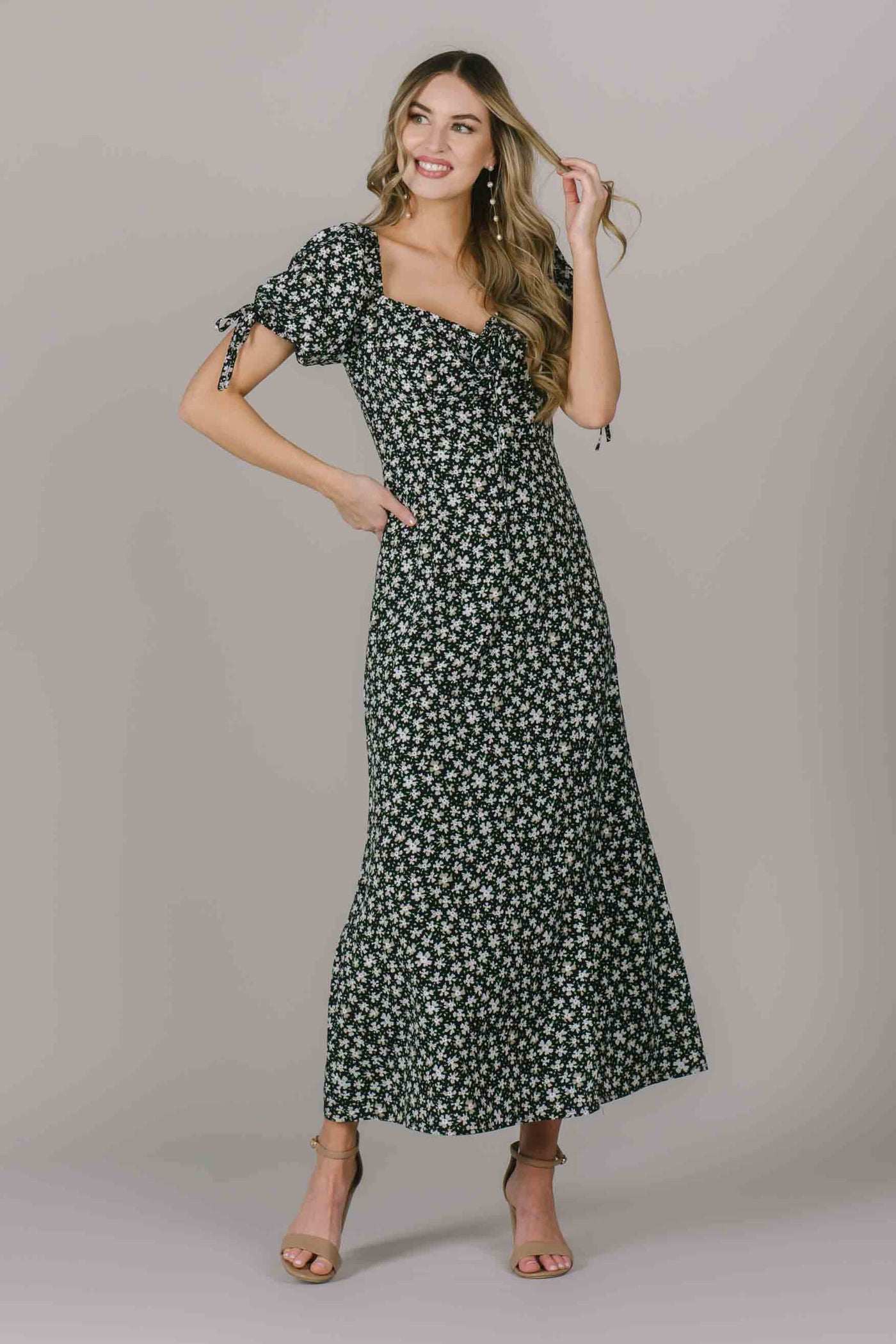 A full length modest dress with a white floral pattern, sweetheart neckline, puff sleeves with a bow and defined waistline.