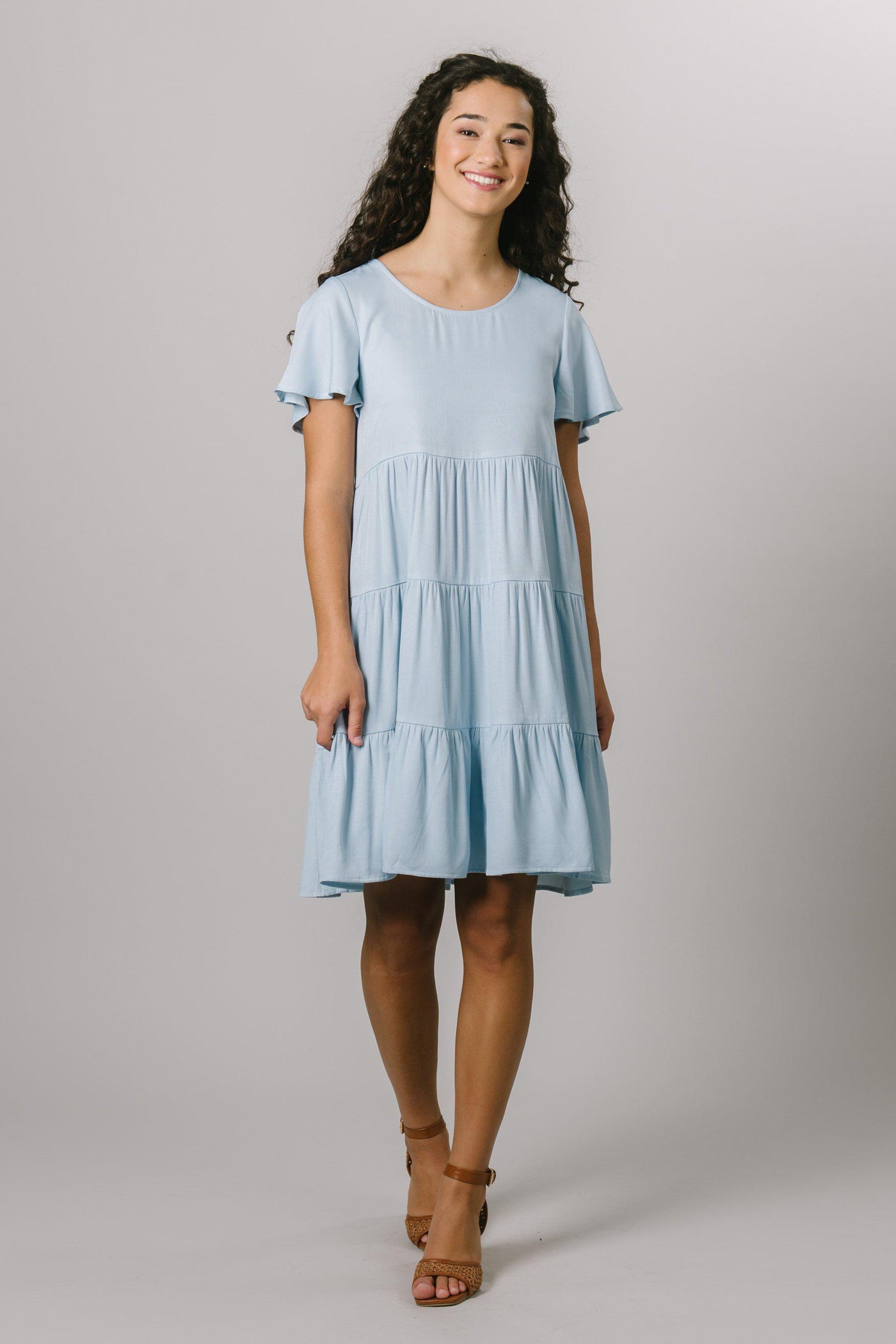 A modest, loose fitting everyday dress that features a scoop neck and flutter sleeves in baby blue.