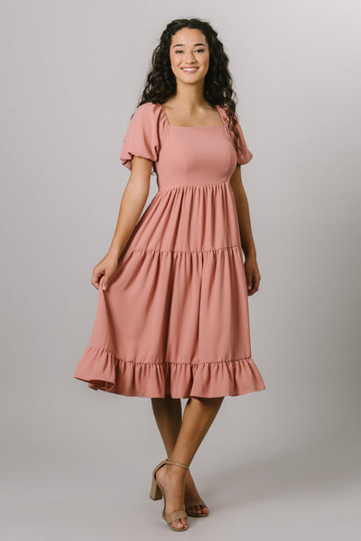 A smocked tiered midi dress with a square neckline and 3/4 length puff sleeves in canyon rose. Modest Dresses - Everyday Modest Dresses - Bridesmaid Modest Dresses. 