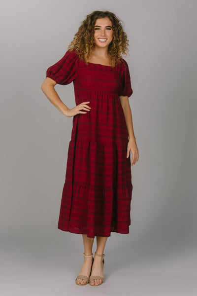 Modest everyday dress featuring a tiered, midi length skirt. This red dress has a square neckline and puffed sleeves. This perfect modest dress has a horizontal striped pattern.