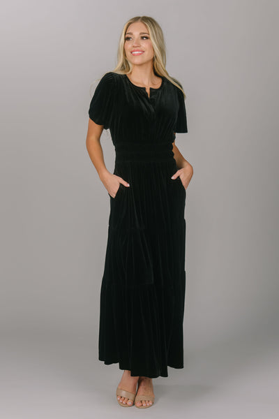 Modest everyday and bridesmaid black colored dress. This dress is velvet, has a v-neckline, and a tiered skirt. This modest dress for women is floor length and super comfortable.