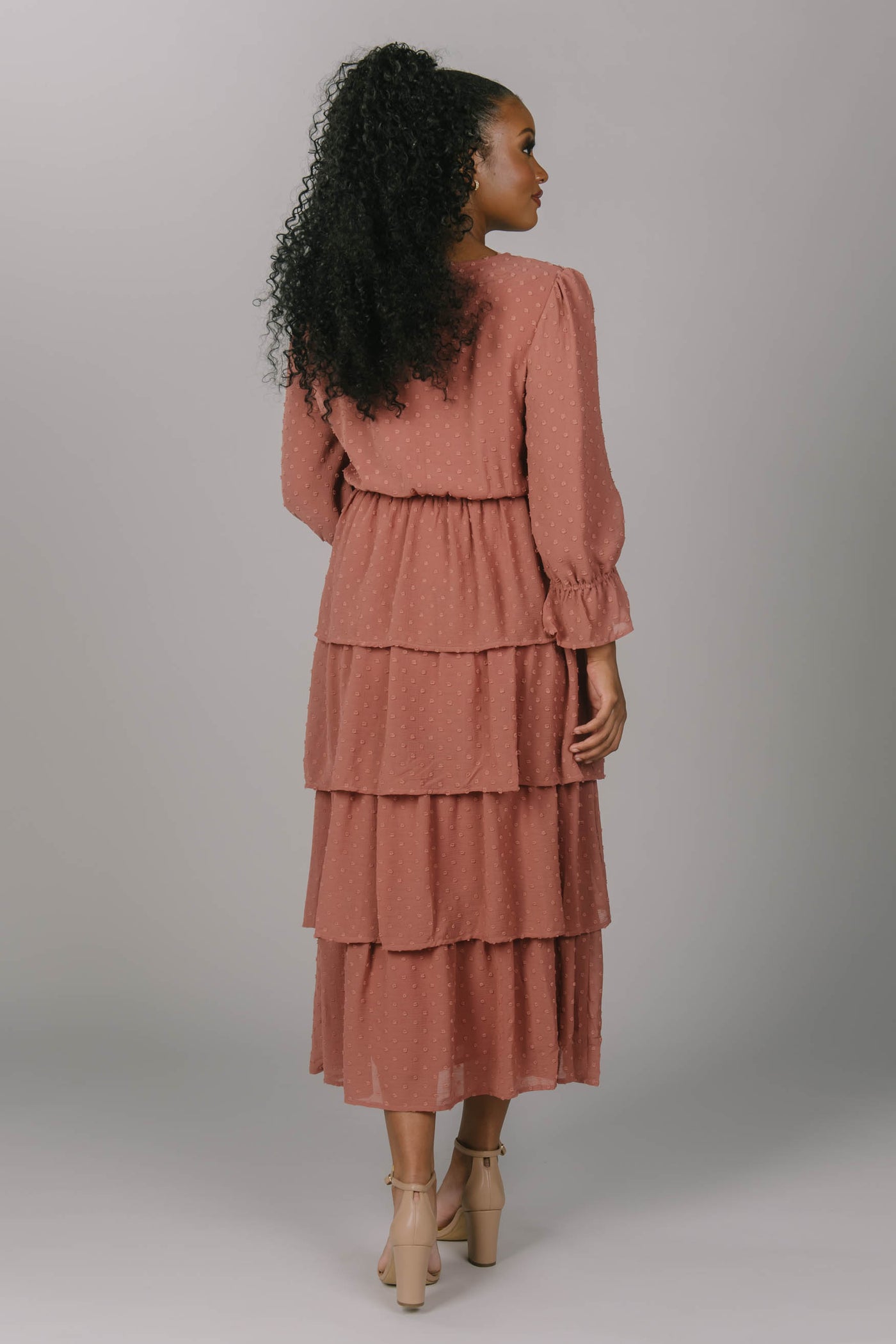 Back view of mauve modest bridesmaid dress. The skirt is tiered and the sleeves are tucked to create a bishop sleeves. It is covered with swiss dots.