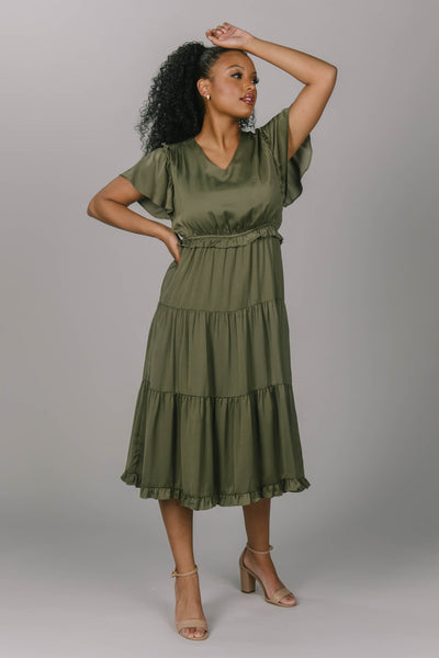 Front view of an olive modest bridesmaid dress. It has a v-neckline and flutter sleeves. Its draping and tiered skirt make for the perfect modest bridesmaid dress.