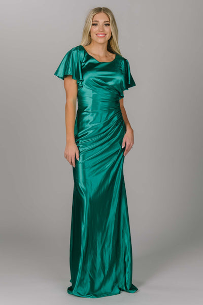 Modest prom dress that is fitted with flutter sleeves. This dress is an emerald satin color that has shine. The dress has a scoop neckline and is perfect for any modest prom girl. 